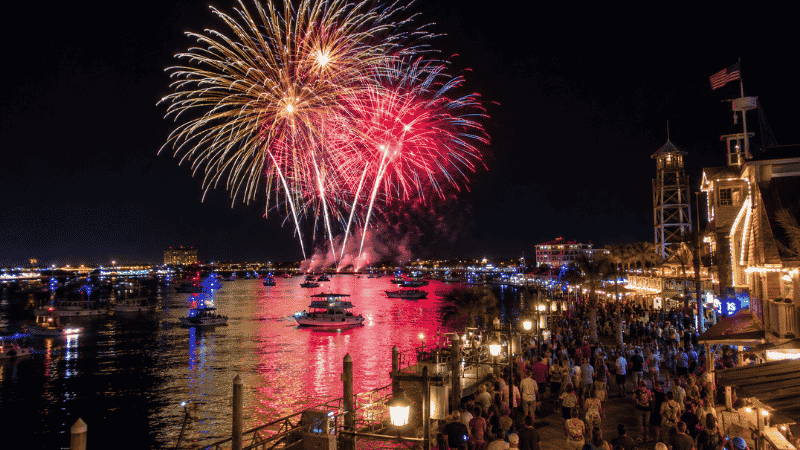 Summer fireworks display over Destin Florida harbor at night with colorful reflections on the water