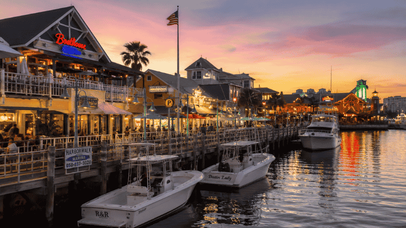Destin Harbor Boardwalk Florida at dusk with waterfront restaurants and boats moored along the dock