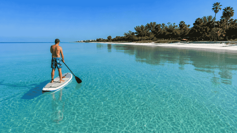 Person paddleboarding on calm turquoise Gulf water near Siesta Key Beach Florida