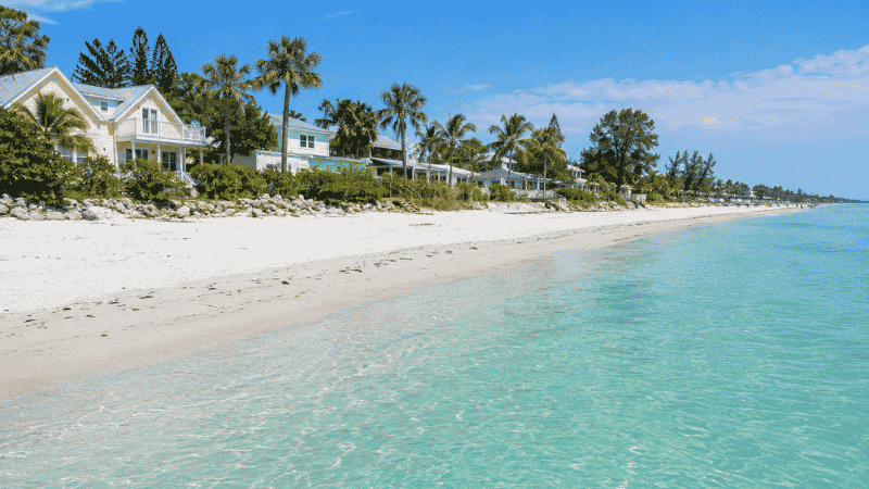 Anna Maria Island Florida beach showing charming low-rise beach cottages and palm trees with calm turquoise Gulf water and no high-rise buildings