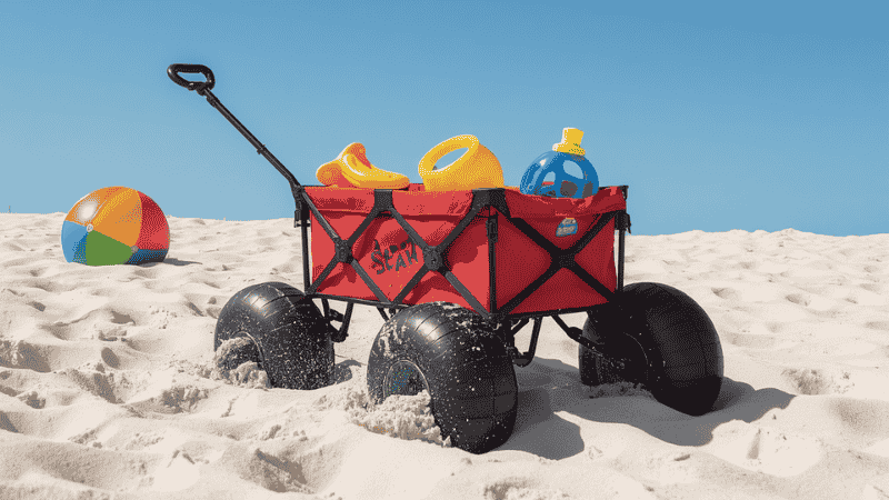A folding beach buggy equipped with a huge "balloon tire" is effortlessly gliding through the soft white sand, demonstrating the best way to transport equipment on the Florida beach.