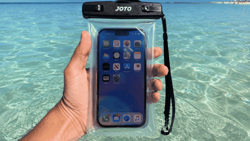 Person holding a clear waterproof phone pouch in shallow turquoise Gulf water at a Florida beach