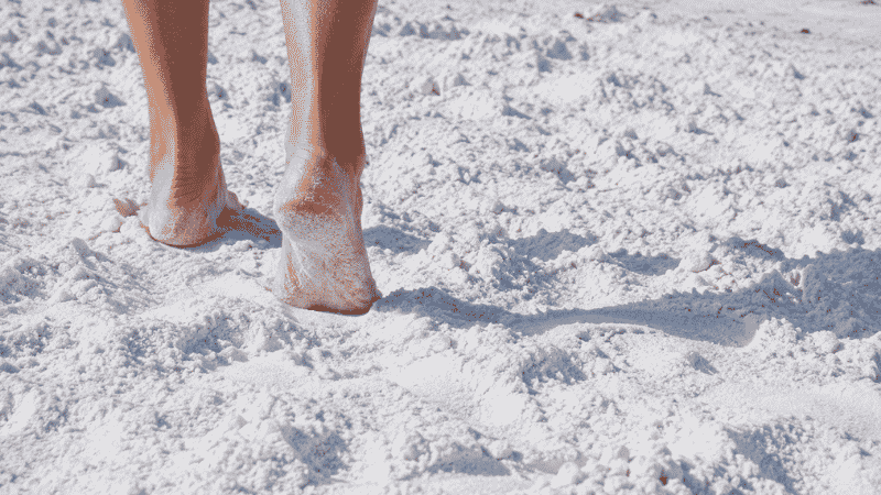 Close up of Siesta Key Beach Florida showing the brilliant white 99 percent pure quartz sand with bare feet walking on cool sand