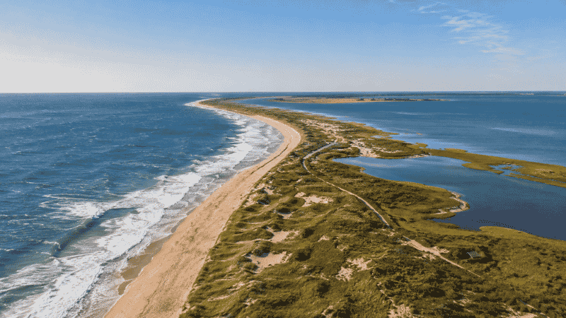 Aerial view of Cape Cod Massachusetts coastline showing the curved barrier sandbar with Atlantic Ocean and calm Cape Cod Bay on opposite sides