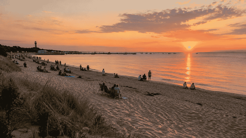 Herring Cove Beach in Provincetown Cape Cod at sunset with warm orange sky reflecting on the water and families watching from the shore