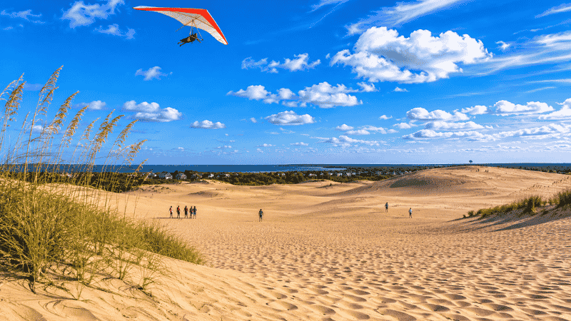 Jockey's Ridge State Park Outer Banks North Carolina showing the tallest natural sand dunes on the East Coast with a hang glider in the blue sky