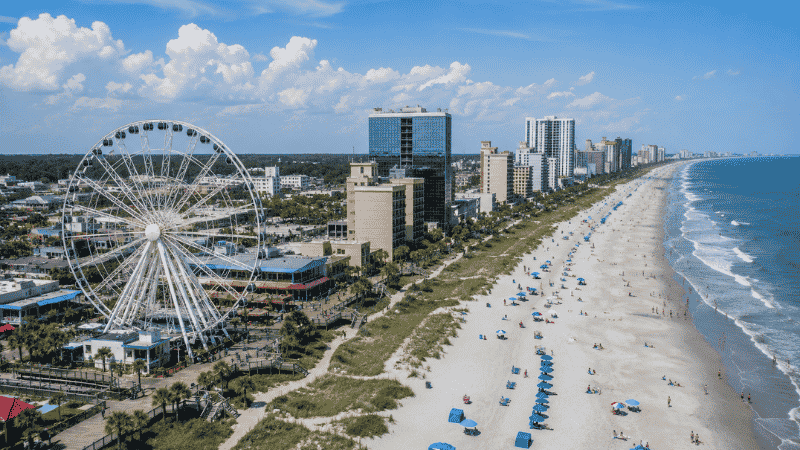 Aerial view of Myrtle Beach South Carolina showing the boardwalk and SkyWheel Ferris wheel along the wide sandy Atlantic beach