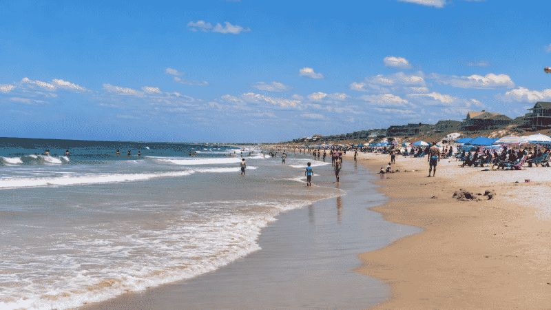 Nags Head beach at Outer Banks North Carolina showing wide sandy Atlantic beach with families playing in the surf on a bright summer day