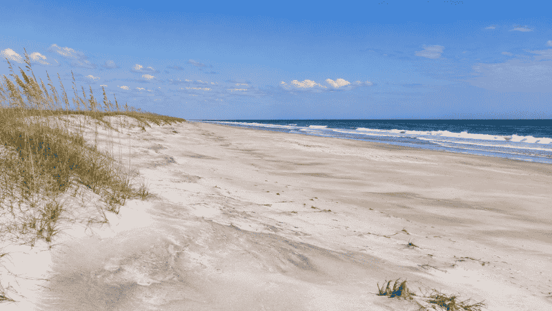 Pristine empty white sand beach at Ocracoke Island in the Outer Banks North Carolina with wild undeveloped shoreline and sea oats on dunes