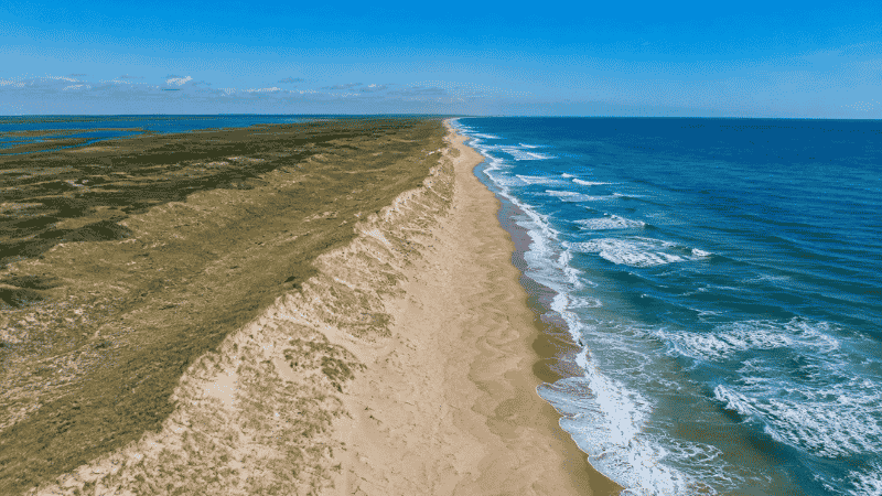 Aerial view of Outer Banks North Carolina barrier islands showing wide wild Atlantic beach and rolling sand dunes with natural undeveloped coastline