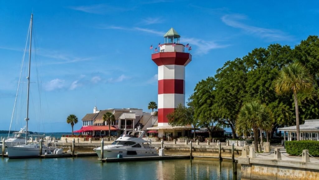 Red and white striped Harbour Town Lighthouse at Hilton Head Island South Carolina with sailboats moored in the marina and blue sky