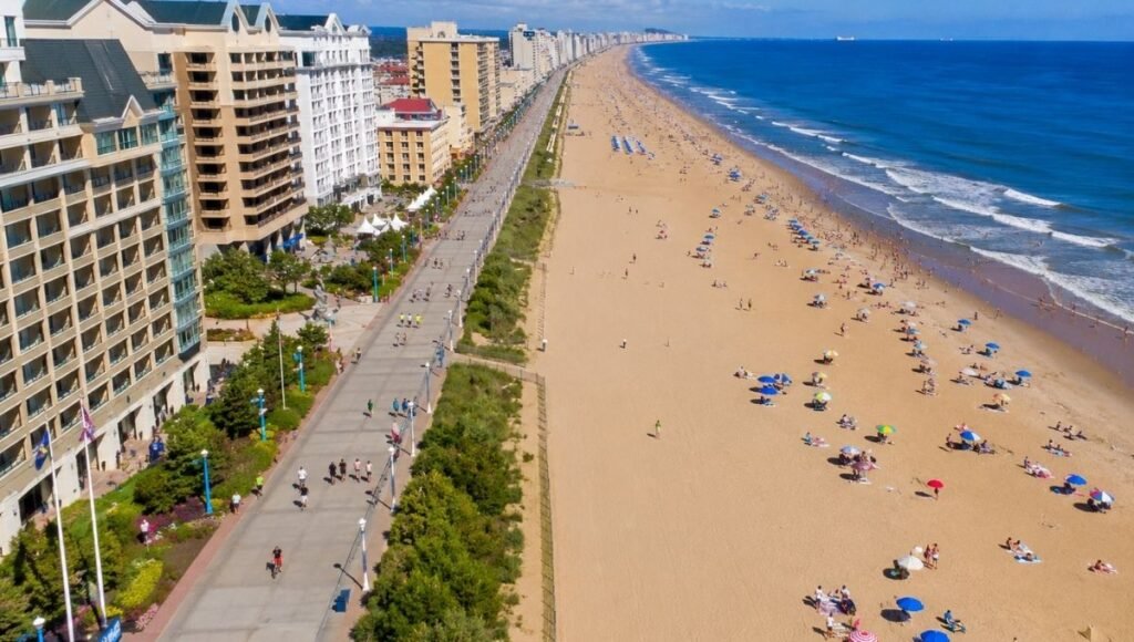 Aerial view of Virginia Beach oceanfront boardwalk showing three mile paved promenade between resort hotels and wide Atlantic beach on a bright sunny summer day