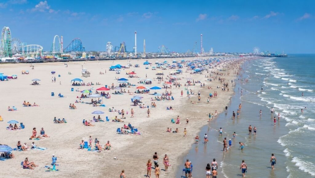 Wildwood New Jersey wide free beach showing the vast expanse of white sand from the boardwalk to the Atlantic Ocean with Morey's Piers visible in the background
